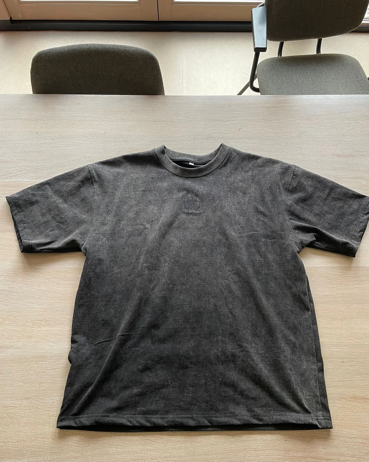A raw phone photo of a t-shirt on a table before VISUAILS